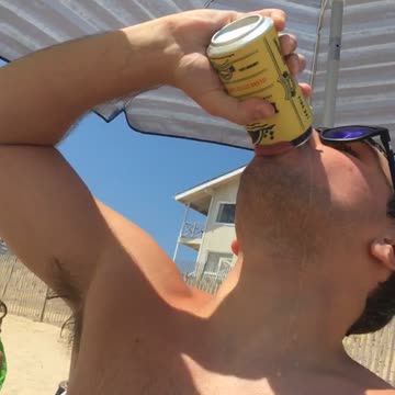 Shirtless guy drinks beer and spills it on himself