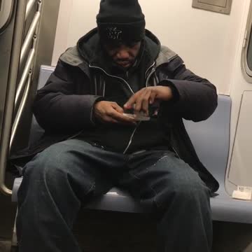 Man rolls cigarette while sitting on subway