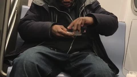 Man rolls cigarette while sitting on subway