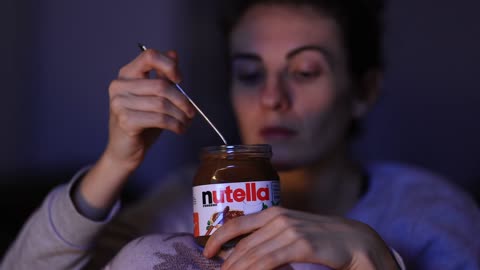 young girl watching TV and eating nutella