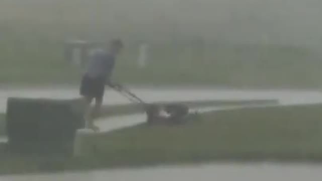 Man Goes On Mowing His Lawn In Middle of Storm