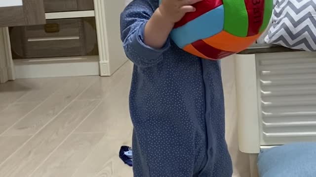 Cute baby try to learn how to play basketball at home under mom coaching