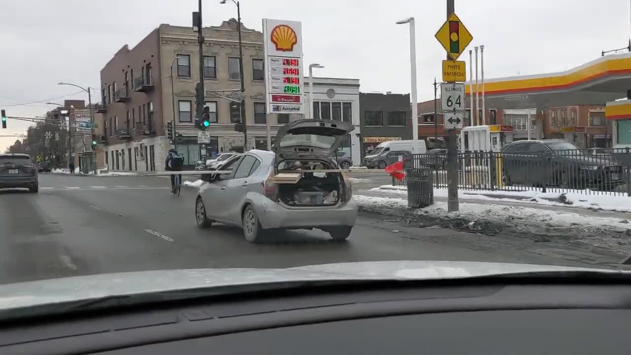 Subcompact Car Driving With Long Wooden Boards Sticking Far Out