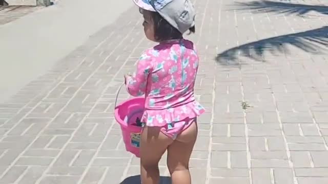 a beautiful child walking on the beach sidewalk very hot summer