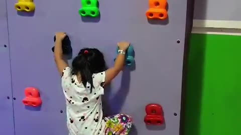 Cute little girl climbing on wall