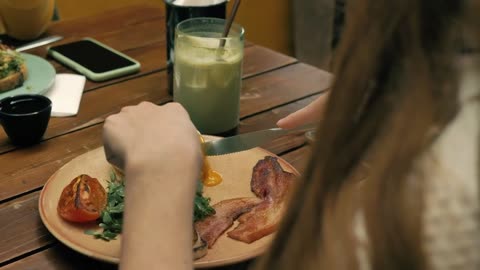 Hands of a girl with cutlery eating in a restaurant