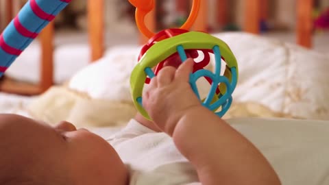 Little baby playing with toys on his bed