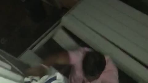 Guy in pink shirt tries to climb from 2nd story balcony onto roof and falls