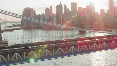 Traffic moves across a suspension bridge into a city