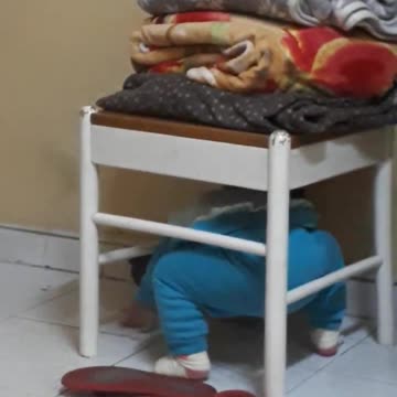 Zahra crawling along chair