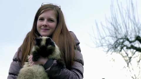 Woman holding cat while it bites her hand.