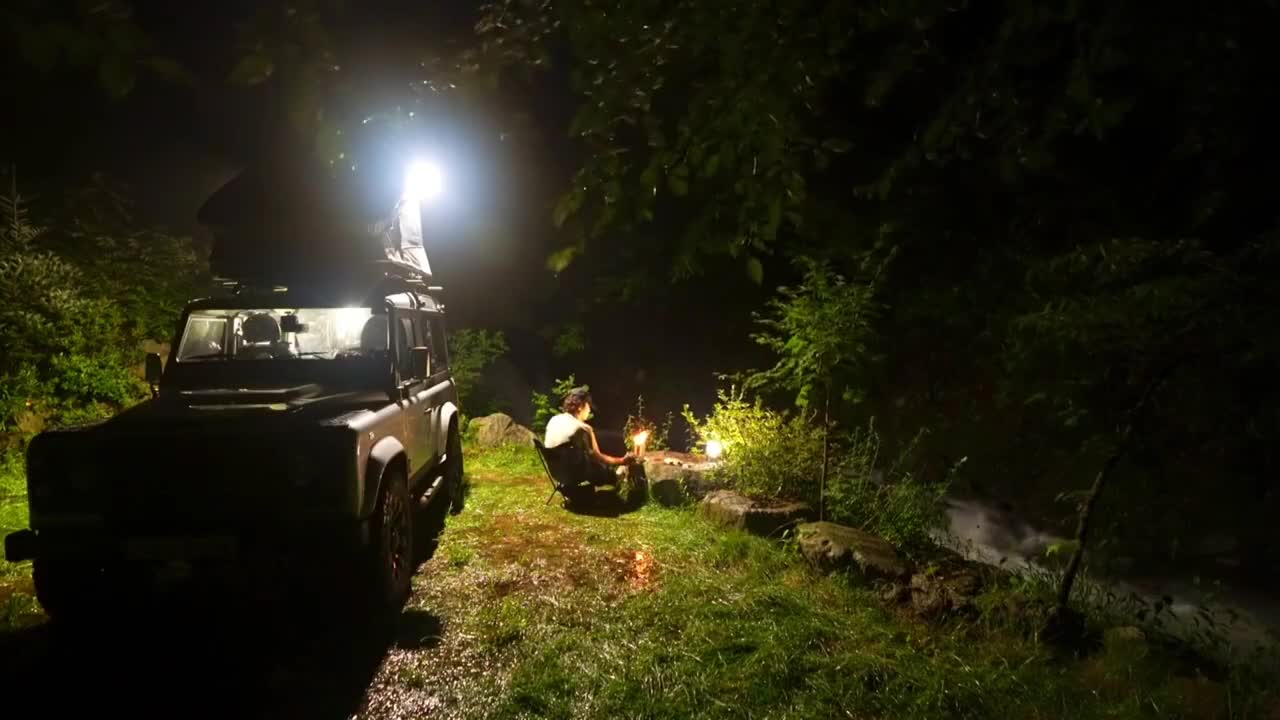 A person's car camping, enjoy the white noise of water flow