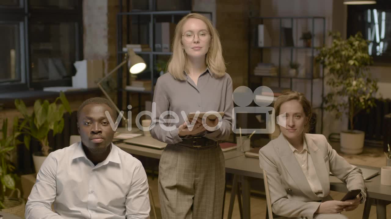 American Man Employee And Female Coworker Sitting On A Chair And Looking At Camera In The Office 1