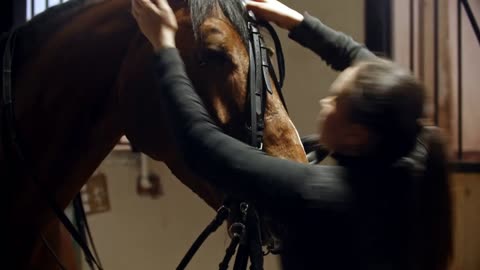 Riding a horse - young woman rider puts reins on her horse