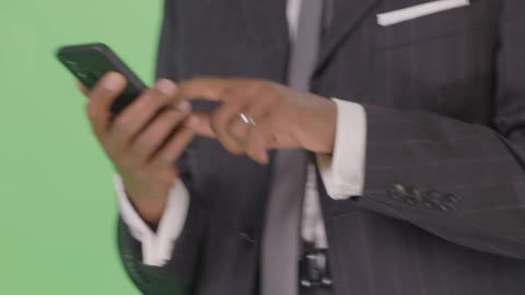 CU Businessman texting while walking on green screen