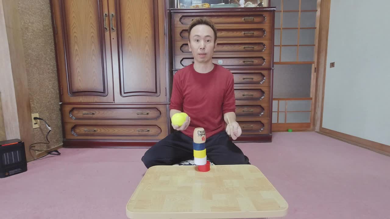 Guy Knocking Away a Daruma Doll Piece While Juggling