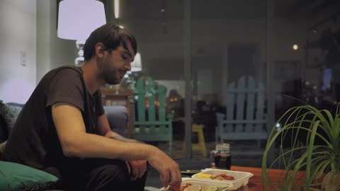 Man eats watching television on a rainy night