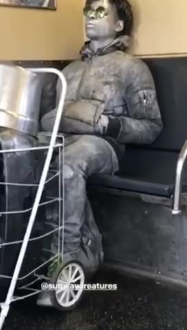 Silver body spray paint man sits with sunglasses in subway