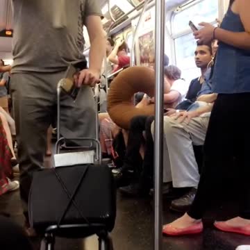 Guy pushing speaker playing trumpet subway