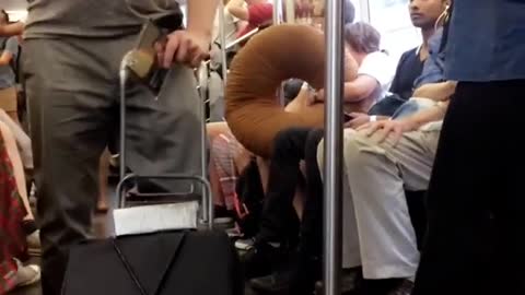 Guy pushing speaker playing trumpet subway