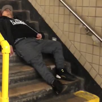 Man black shirt red hat asleep on subway stairs