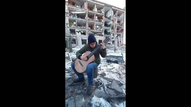 Ukraine.The guy plays the guitar near his house destroyed by a bomb