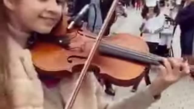 A little girl is totally amazed by her live violin performance