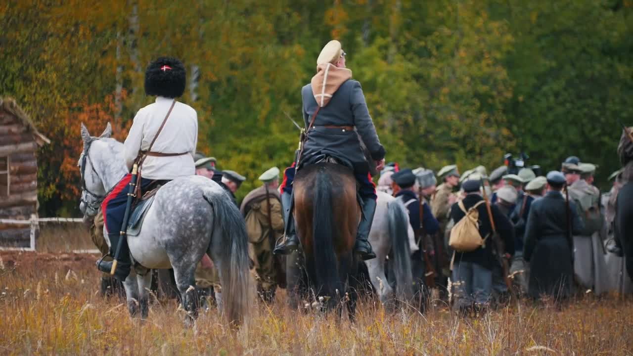 A military assembly - an area surrounded by soldiers - two men standing on the horses on the field