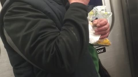 Drunk man black jacket struggle to eat sandwich