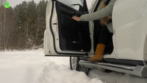 Young woman driver coming out from car parking on winter forest landscape