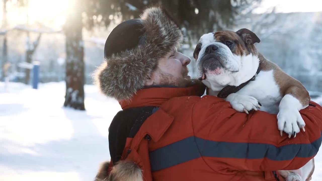 young bearded man hugging and gently kissing his cute friend English bulldog