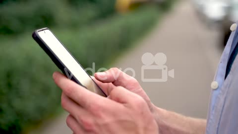 Close Up Of A Man Using His Smartphone And Smiling Outdoors