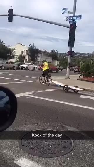Guy on bike with his surf board behind him