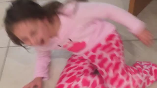 English girl in pink shirt runs across wet floor and slips in kitchen