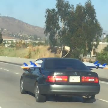 Person driving on freeway with surfboard through back seat windows
