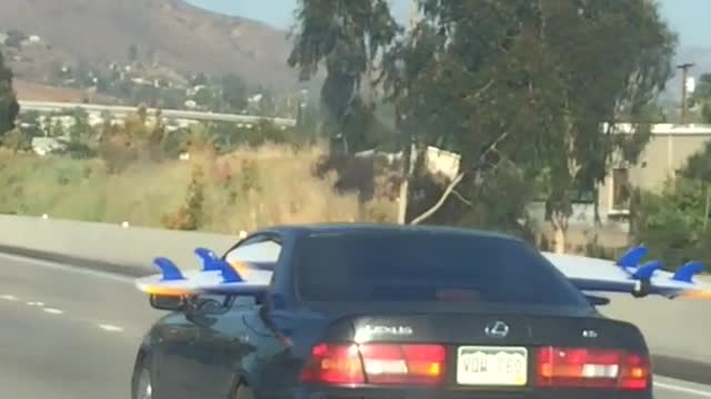 Person driving on freeway with surfboard through back seat windows