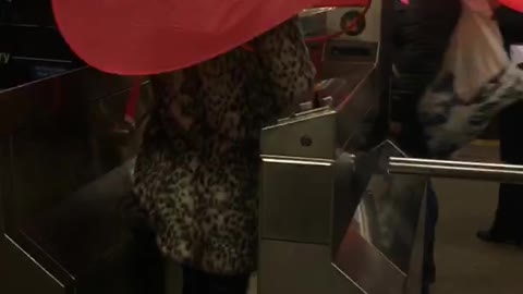 Two people subway turnstile red umbrella hats