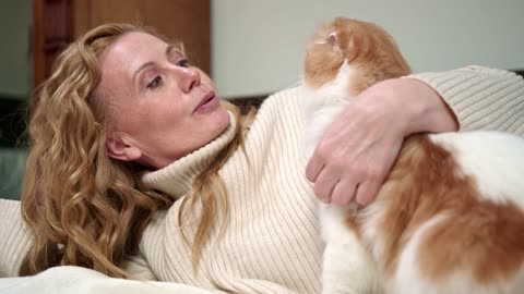 A Woman Petting Her Cat On The Bed