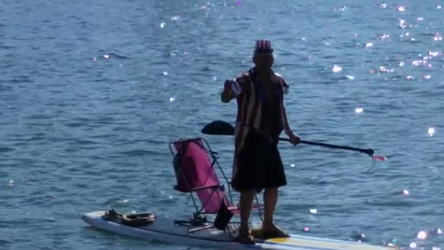 Guy dressed like uncle sam paddleboards on lake