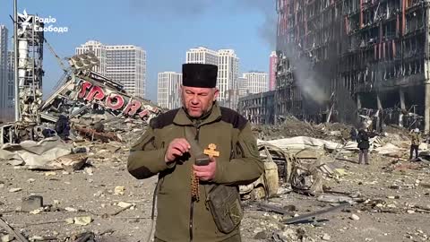 Chaplain Mykola Medynskiy reads a prayer next to the bombed-out shopping mall in Kyiv