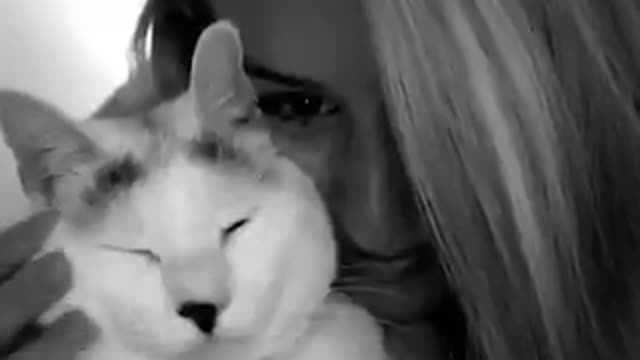 Blonde girl pets a white cat and smiles