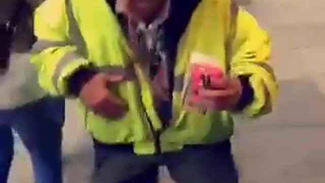 Safety vest man dances next to passed out girl being held up by friends