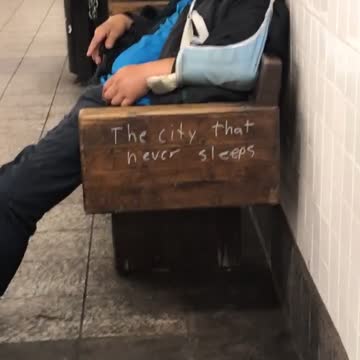 A man in a blue jacket asleep on bench
