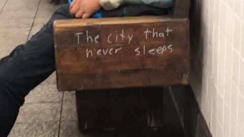 A man in a blue jacket asleep on bench