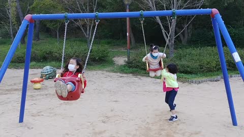 Two girls are riding on a swing.