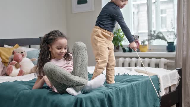 kids-playing-catch-the-bait-with-their-cat-in-the-bedroom