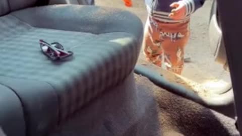 Silly toddler "helps" mom clean the car