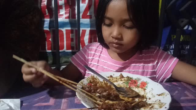 Little Girl Like to Eating satay with peanut sauce