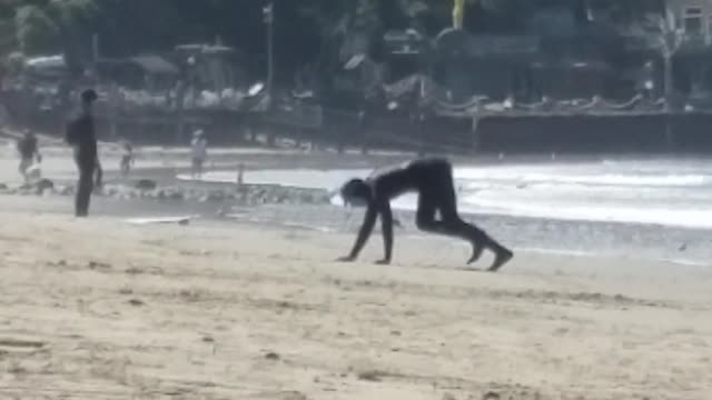 Man in black wetsuit crawling towards beach