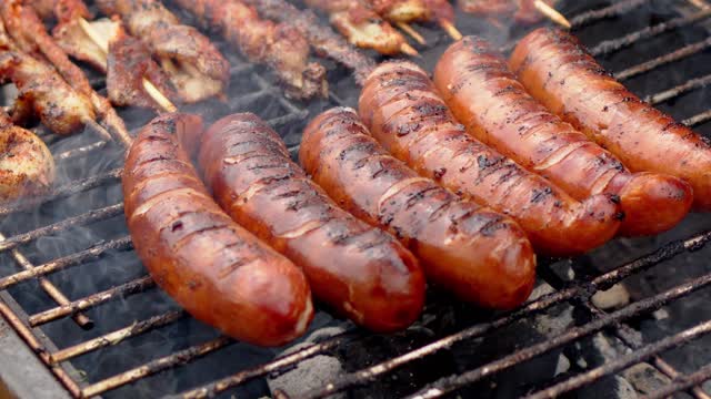 Hot tasty grilled sausages frying on smoking barbecue